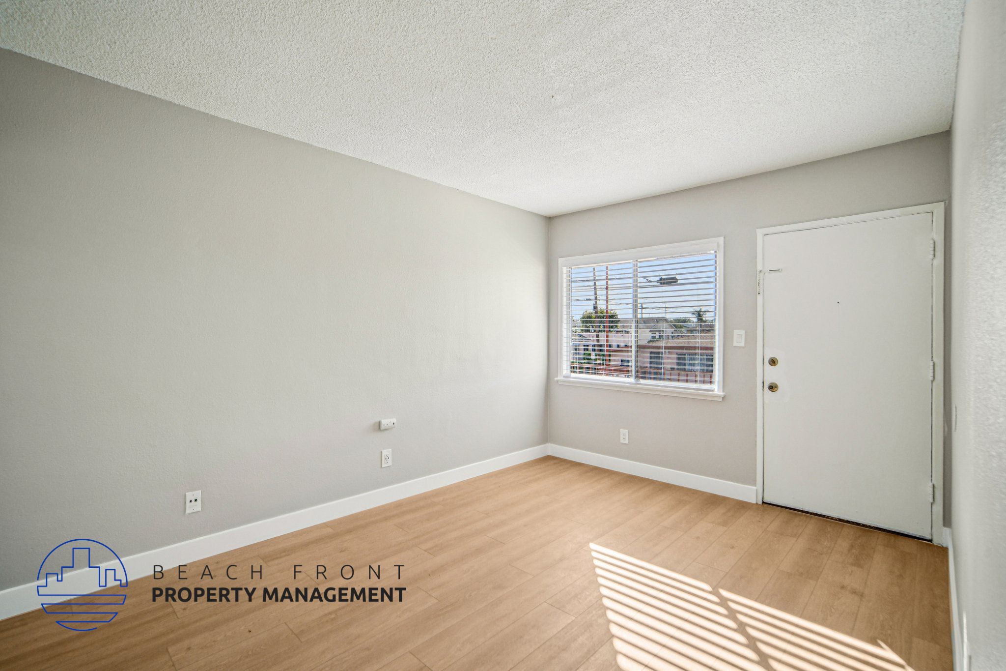 A room with a wooden floor and a window with blinds.